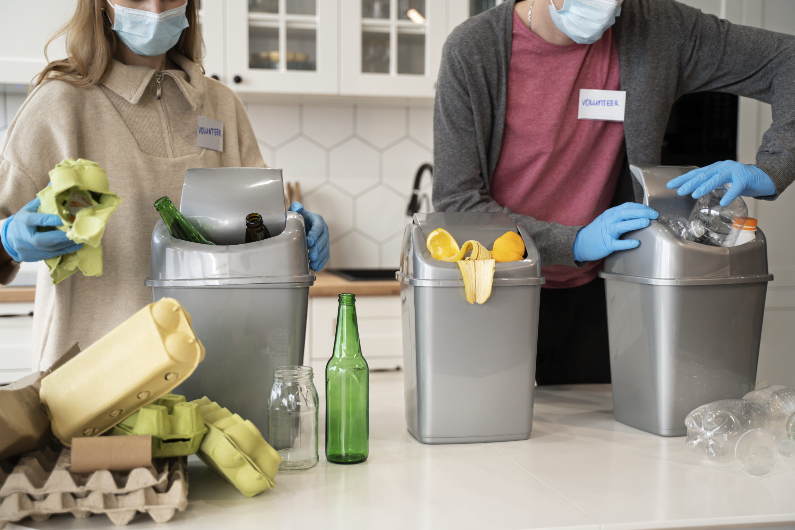 Deux personnes triant dans trois petites poubelles grise